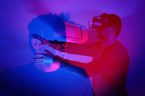 Photo of He is discovering metaverse by using VR glasses under neon lights