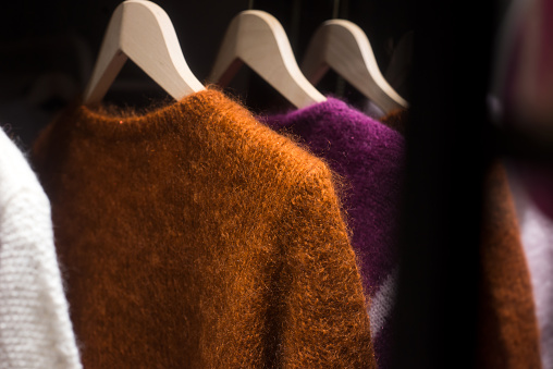 closeup of colorful woolen pullover on hangers in a woman fashion store showroom