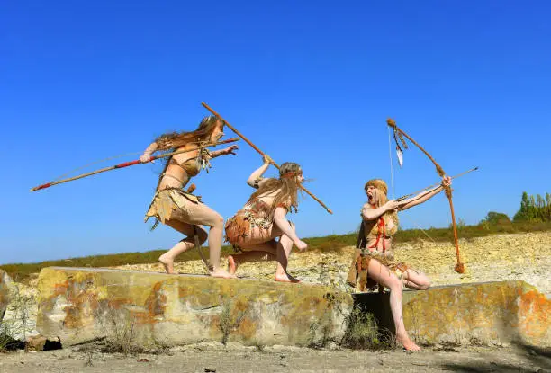 Three girls are dressed as Stoneage warriors. They 
are covered with mud and dirt and are seen attacking, 
screaming and shouting as they run over large boulders.