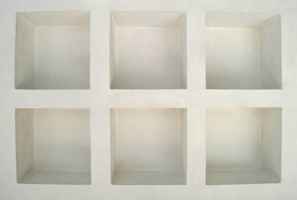 Off white or pastel cream colored concrete structure built with compartments or cubical hollows in a wall as if a display area or shelves or compartments that are empty and blank. There are six equal sized cubes like pigeonhole or cubbyhole.
