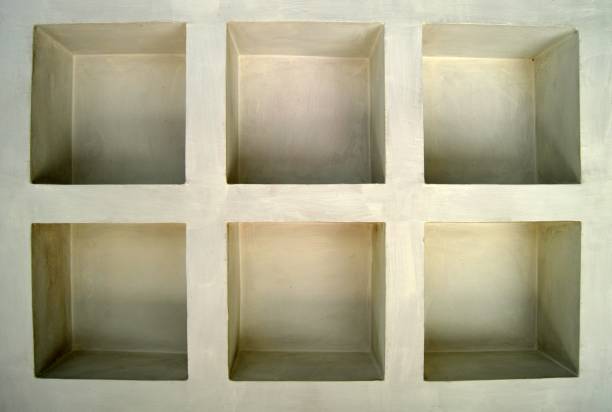 Off white or pastel cream colored concrete structure built with compartments or cubical hollows in a wall as if a display area or shelves or compartments that are empty and blank. There are six equal sized cubes like pigeonhole or cubbyhole.
