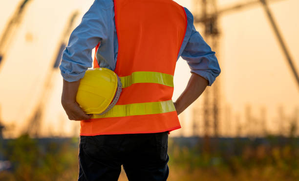 istock Back side view of Man holding White helmet close up. Construction workers working on construction site 1362205209