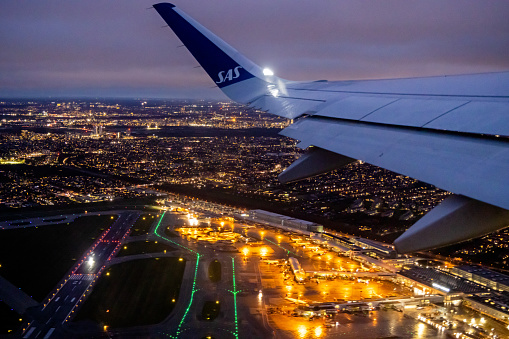 View to Copenhagen Airport under the wing of an departing Airbus 320 from Scandinavian Airlines on a dark winter sky