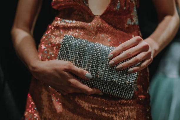 Female hands holding a small metal silver handbag.