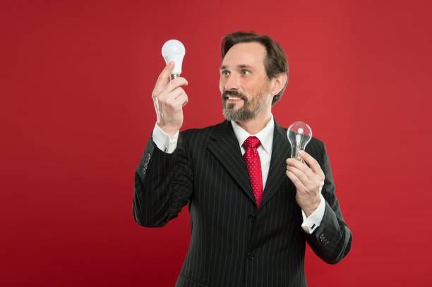 Idea for business. Environment friendly idea. Genius idea. Light up your business. Man bearded businessman formal suit hold light bulb on red background. Symbol of idea progress and innovation.
