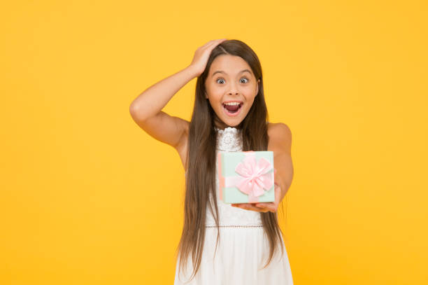 istock Extremely impressive. Perfect package. Child happy face holds big gift box yellow background. Kid girl delighted gift. Girl adorable happy face celebrate birthday. Kid happy love birthday gift 1362214447