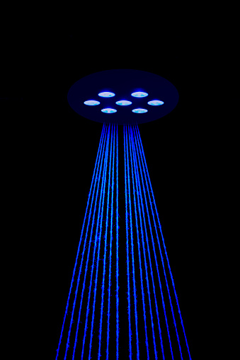 Lines of blue light are fanning out in a triangle shape. Close up of stage lighting with yarn. In a theater.
