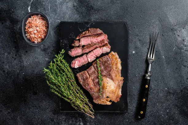 Roasted bbq Chuck Roll beef steaks with herbs. Black background. Top view.