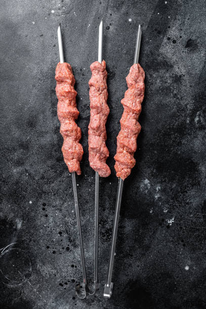 Raw mince lamb meat shish kebab on butcher table. Black background. Top view Raw mince lamb meat shish kebab on butcher table. Black background. Top view. turkish sausage stock pictures, royalty-free photos & images