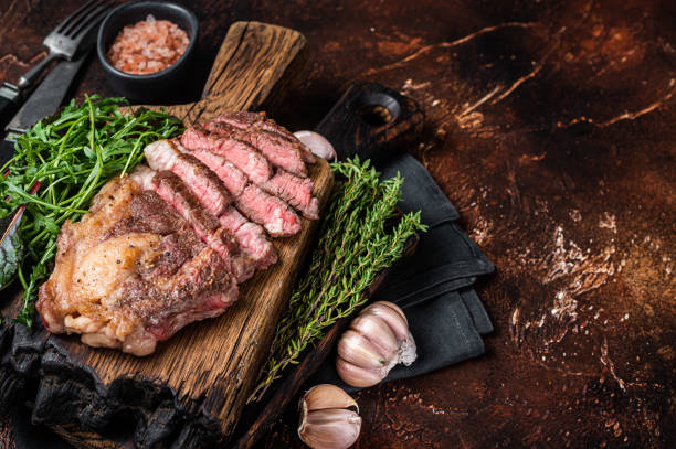 steak de bœuf chuck roll grillé avec salade sur planche en bois. fond sombre. vue de dessus. espace de copie - eye fillet photos et images de collection