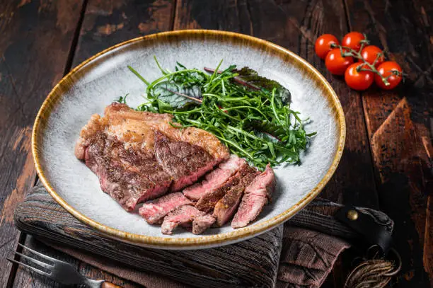 BBQ Roasted Chuck Roll  Tender beef steak with salad in plate. Wooden background. Top view.