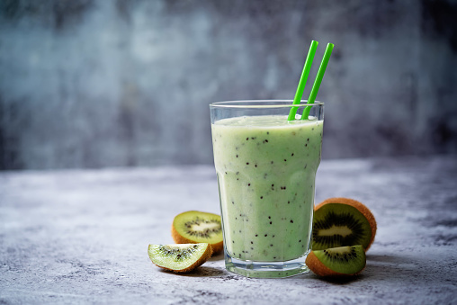 Kiwi banana smoothie in a glass ith kiwi slices. toning. selective focus