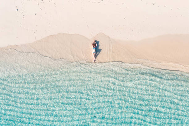 istock Woman lying back on white sand beach 1362220315