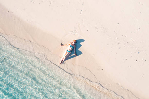 istock Woman lying back on white sand beach 1362220333