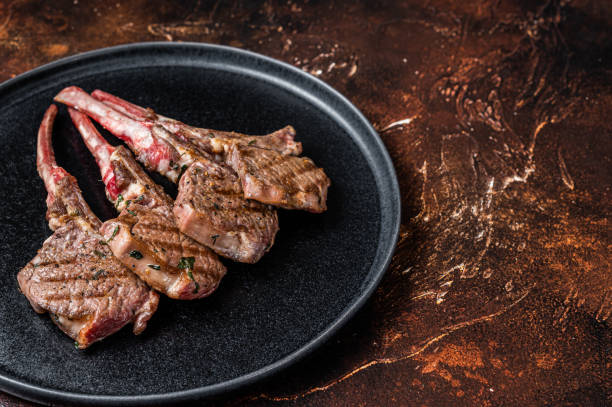 istock BBQ Grilled lamb chops steaks in a plate. Dark background. Top view. Copy space 1362220949