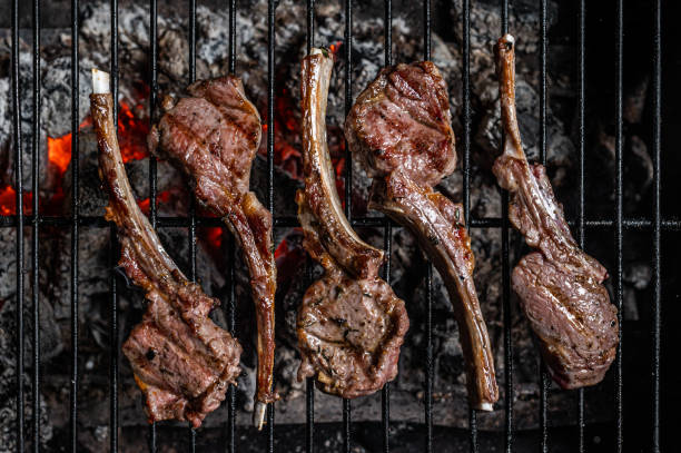 Grilled lamb mutton chop steaks on barbecue, outdoor BBQ grill with fire. Top view Grilled lamb mutton chop steaks on barbecue, outdoor BBQ grill with fire. Top view. rack of lamb stock pictures, royalty-free photos & images