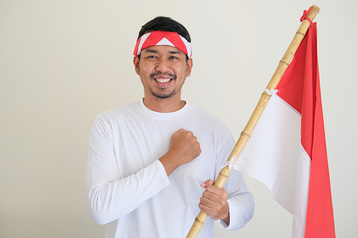 Adult Asian man smiling while holding Indonesia national flag