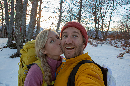 Couple taking selfies during winter hike in the forest, Switzerland