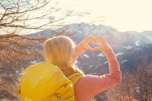 Photo of Woman on a hike makes a heart shaped finger frame