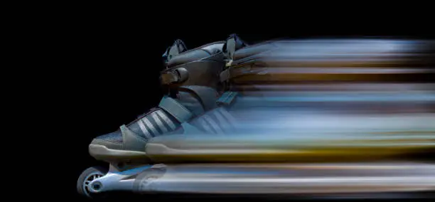 Pair of inline skating shoes with movement blurred light trails behind