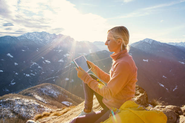 istock Young hiker sitting on mountain top using digital tablet at sunrise 1362227681