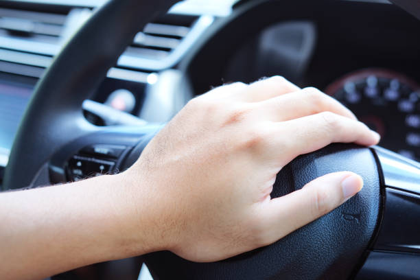 istock Car driver hand pressing horn in steering wheels closeup 1362229373