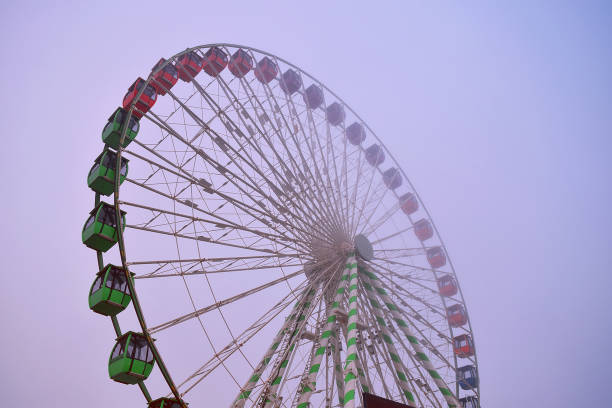 3d rendering of illuminated old ferris wheel at abandoned foggy parking space