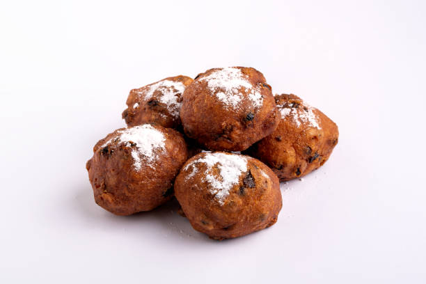 a pile of dutch traditional oliebollen (dough balls) with powdered sugar isolated on white background - oliebollen stockfoto's en -beelden