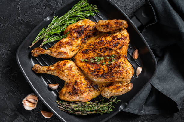 istock BBQ spatchcocked barbecue whole chicken on grill pan. Black background. Top view 1362236475