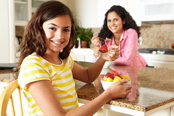 Mother and daughter smiling and eating breakfast