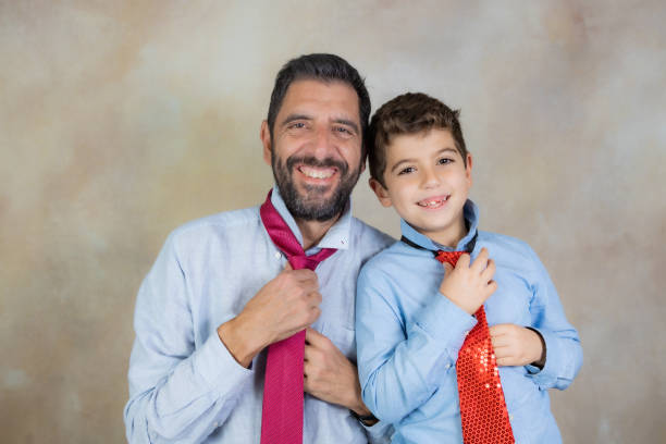 Young man and his son tying their neckties