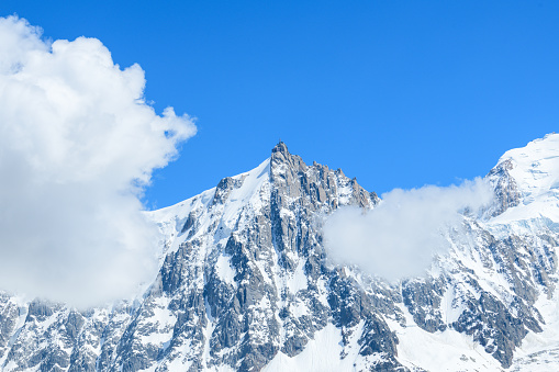 This landscape photo was taken in Europe, in France, in the Alps, towards Chamonix, in summer. We see the Midday Eel under the clouds in the Mont Blanc massif, under the Sun.