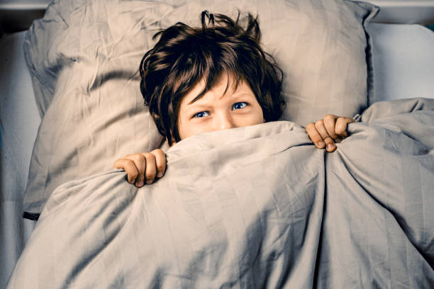 istock Little boy covering his face scared of nightmares 1362253180