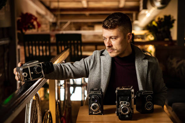 Portrait of confident and handsome Caucasian man, posing with few retro cameras