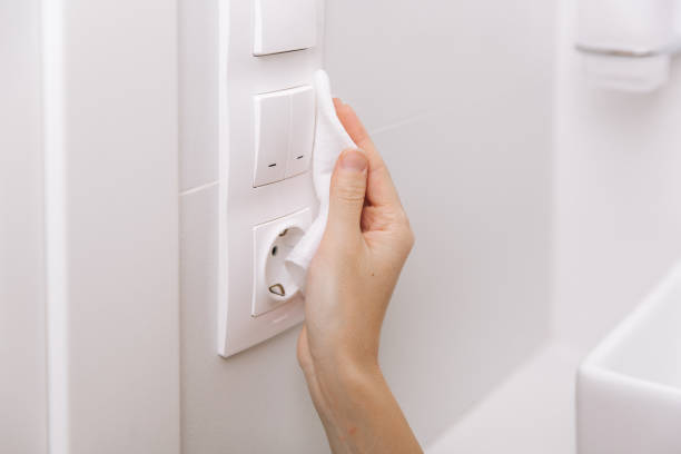 istock Cleaning switches and sockets with a microfiber cloth. Sanitize surfaces prevention in hospital and public spaces against corona virus. Woman hand using wet wipe for cleaning home room door link 1362259612