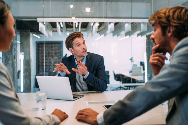 Group of business persons talking in the office. Shot of young couple having a consultation with a financial advisor in the office. Group of business persons in business meeting. Three entrepreneurs on meeting in board room. Corporate business team on meeting in modern office. Male manager discussing new project with his colleagues. Company owner on a meeting with two of his employees in his office. advice stock pictures, royalty-free photos & images