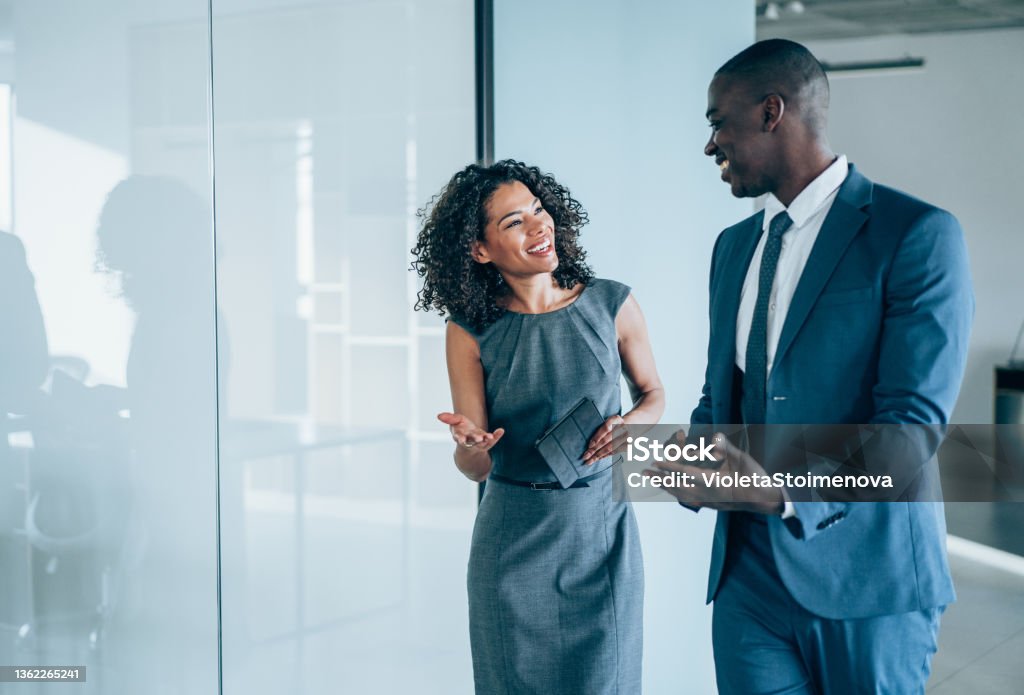 Business people in the office. Shot of two young colleagues having a discussion in modern office. Confident young business people working together in the office. Corporate business persons discussing new project and sharing ideas in the workplace. Business Stock Photo