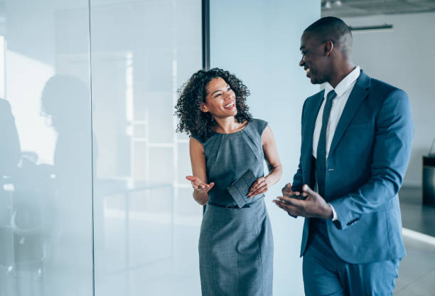 Business people in the office. Shot of two young colleagues having a discussion in modern office. Confident young business people working together in the office. Corporate business persons discussing new project and sharing ideas in the workplace. discussion stock pictures, royalty-free photos & images