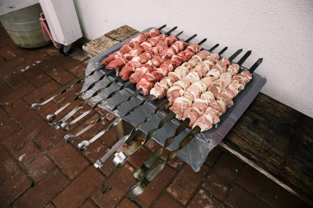 Preparing pork shashlik on a charcoal mangal. Beef grill. BBQ. Marinated meat food cooking on a mangal skewers on the fire. Top view. Outdoor picnic rest. Traditional tasty shish. Smoke. Juicy meal. preparando shashlik de cerdo en un mangal de carbón. parrilla de ternera. barbacoa. comida de carne marinada cocinando en un pincho de mangal en el fuego. vista superior. descanso de picnic al aire libre. shish sabroso tradicional. humo. comida jugosa
