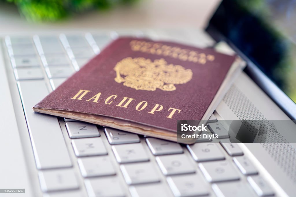 Passport of Russian Federation on a gray laptop keyboard. Identification of the user on the Internet. Prohibition of access to the Internet without passport data. issuing a passport via the Internet Passport of the Russian Federation on a gray laptop keyboard. Identification of the user on the Internet. Prohibition of access to the Internet without passport data. issuing a passport via Internet Computer Stock Photo
