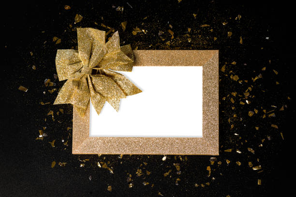 istock New Year's card background.Close-up.Simple minimalistic .Gold frame from glitters with a gold bow on a black background. Greeting cards.Copy space. 1362293381