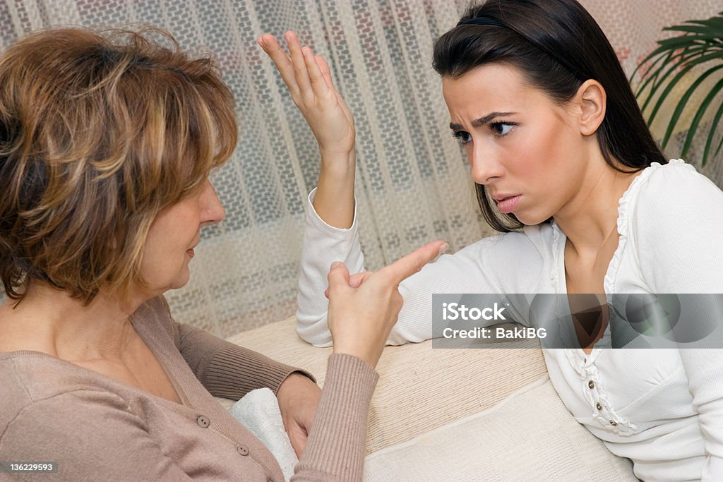 A mother scolding her adult daughter Mother and daughter sitting on the sofa and serious talking. Mother Stock Photo