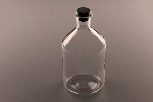 A empty old bottle with a rubber stopper is isolated on a gray background.  The picture has an old sepia and grainy picture effect.  Can be use to symbolize starting out, future, empty, etc.   Empty space for text.