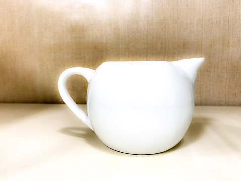 White teapot on display against a textured background.
