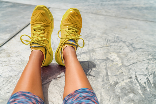 Yellow sneakers girl wearing fashion style activewear colorful running shoes at gym outdoor. POV selfie of footwear.