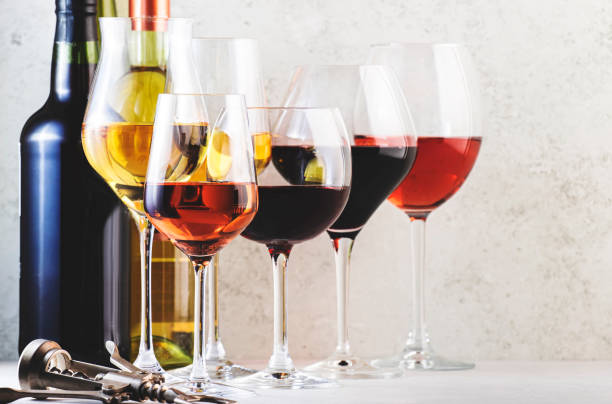 istock Red, rose and white wine glasses set on gray table background. Wine tasting. Hard light and harsh shadows 1362323984
