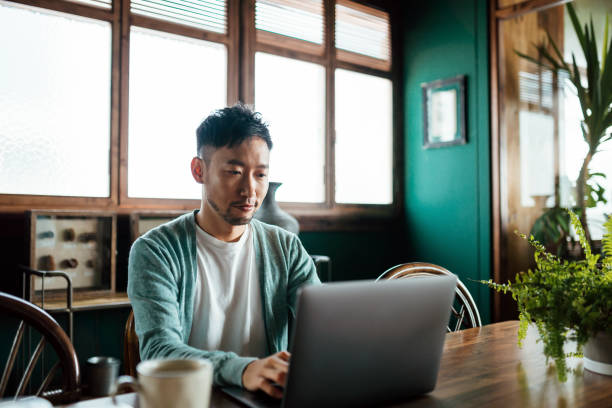 istock Professional young Asian man working from home, using laptop computer in home office. Remote working, freelancer, small business concept 1362328211