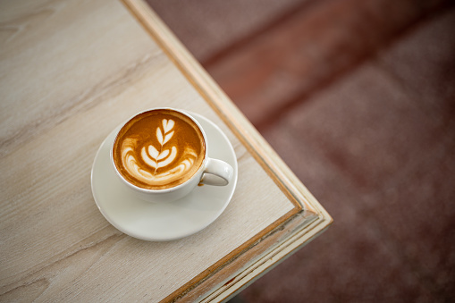 Image of hot latte coffee with latte art on white wooden table background.