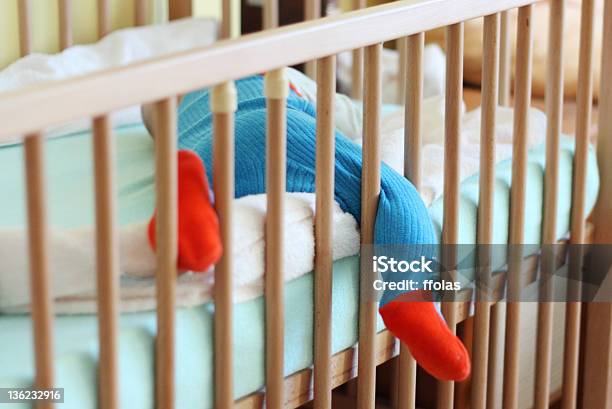 A Baby Boy Sleeping With His Leg Sticking Out From The Crib Stock Photo - Download Image Now