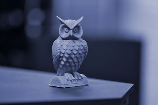 An owl made on a 3d printer stands on a blurry dark background close-up. Progressive modern additive technologies 4.0 industrial revolution. Blue gray color